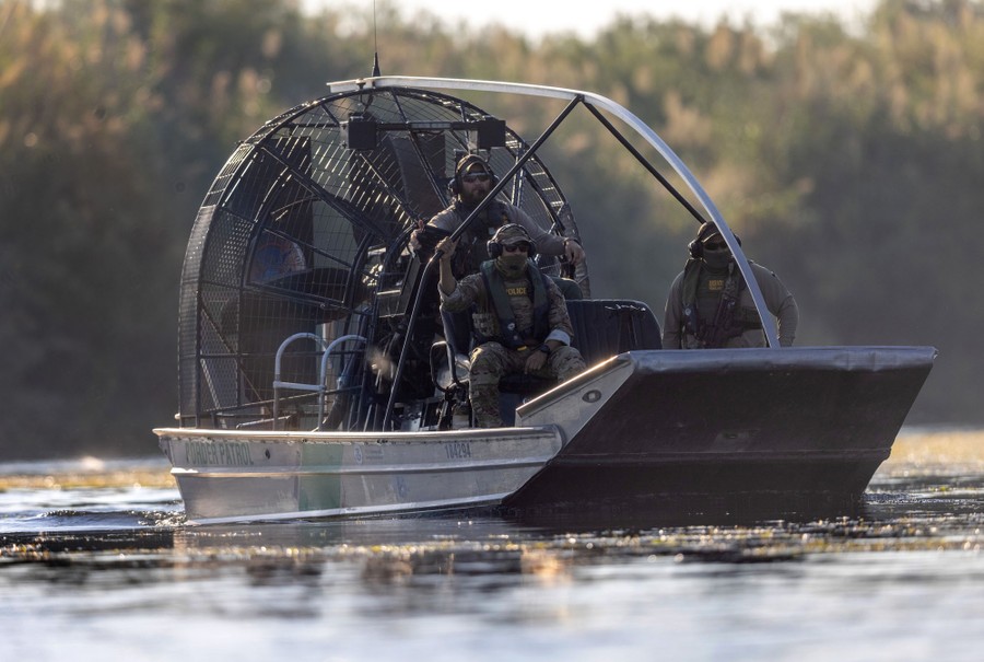 Three U.S. Border Patrol agents float in an airboat on the Rio Grande river.