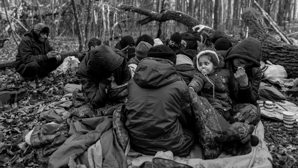 A migrant family sitting on the forest floor in Poland