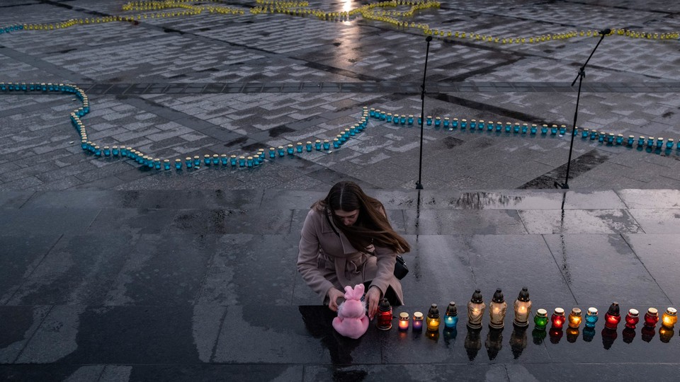 A woman leans over at a candlelight vigil for Ukrainians killed in the towns of Bucha and Irpin.