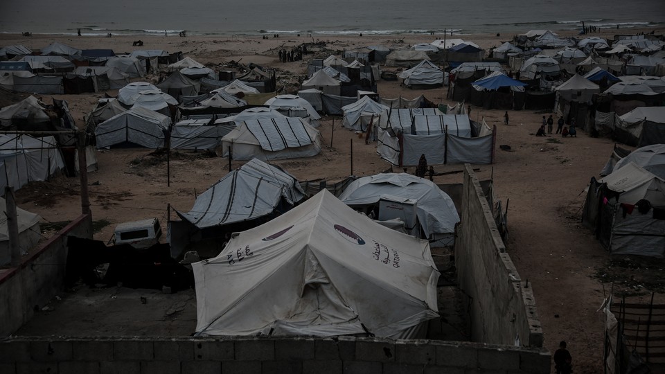 A beach is covered with crude tents for people to live in.