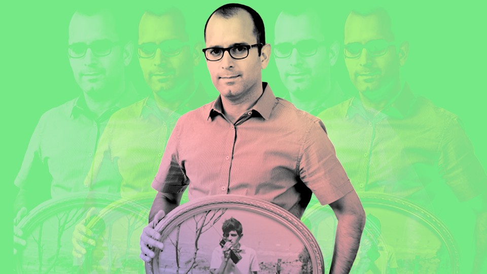 Yaniv Erlich holding a photo of his father as a teenager against a green background