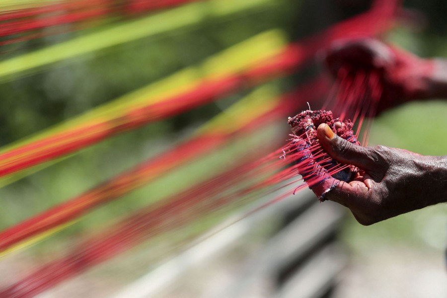 A person handles dozens of colored threads.