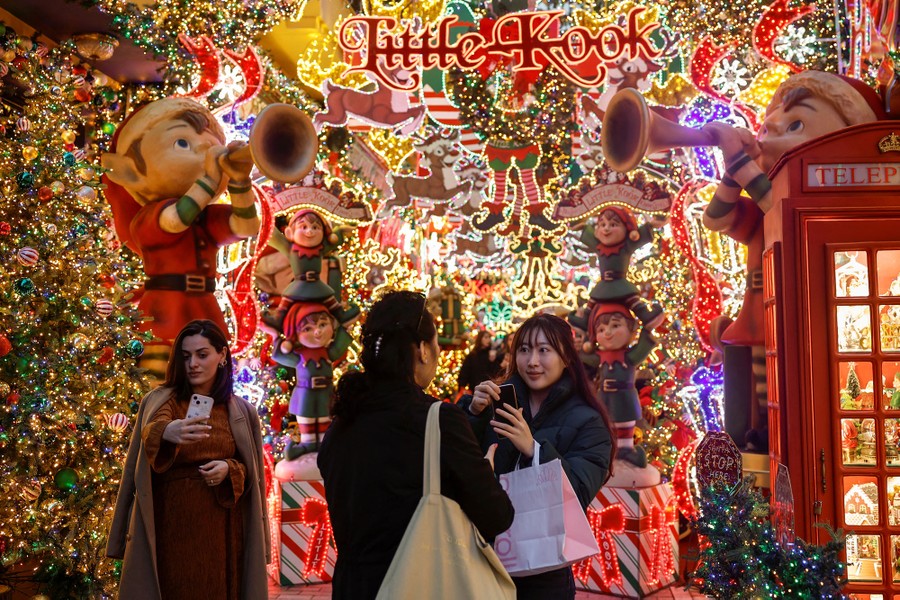 People take selfies and photos in front of Christmas decorations.