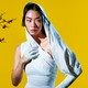 Rina Sawayama wearing a white dress with a hood against a yellow background