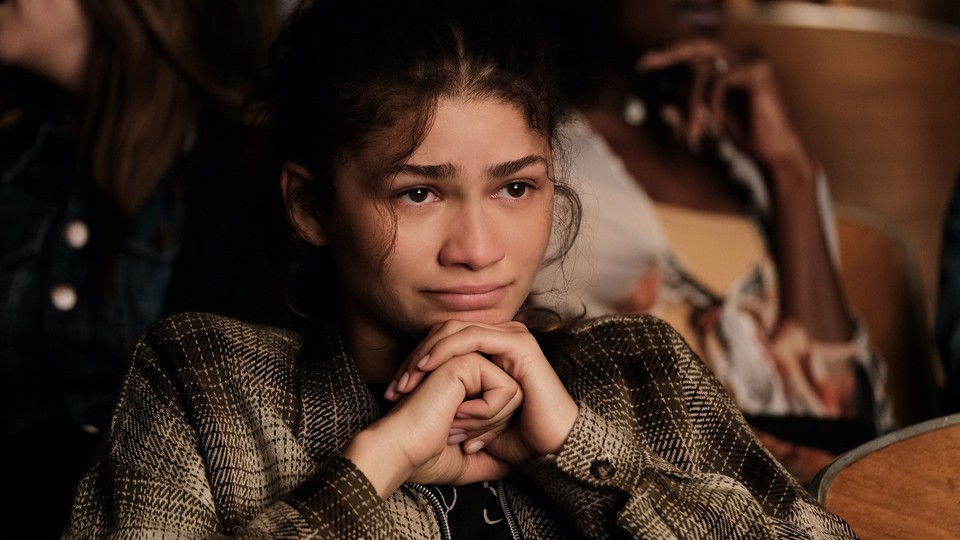 Zendaya with a concerned expression sitting in a school theater in "Euphoria"