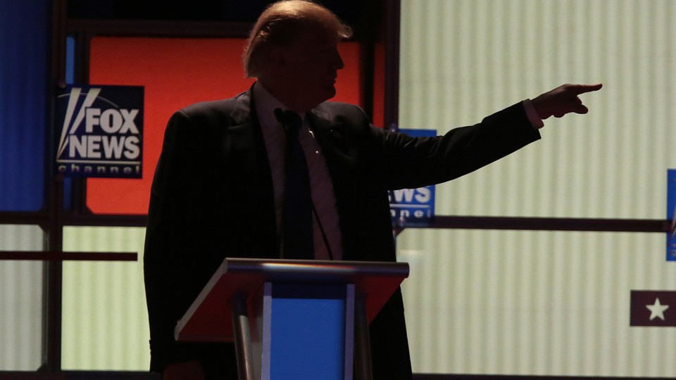 Trump points in front of a Fox News sign.