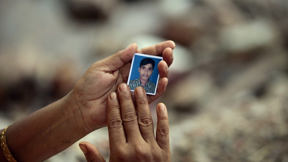 A Bangladeshi woman holds a photograph of a missing worker at the site of the Rana Plaza building collapse in 2013.