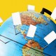 A globe with pins stuck into it; the flags on the pins are white books