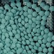 Blue hexagonal pills stamped with the letter 'H' on a mesh conveyor belt