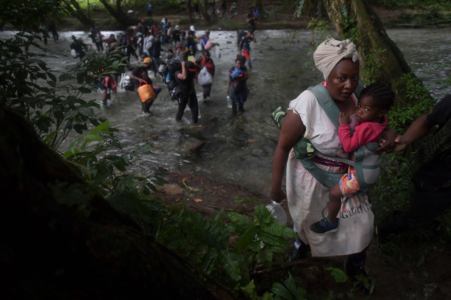 A group of migrants cross a river.