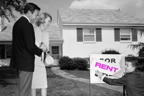 A photo of a couple looking at a "For Rent" sign.