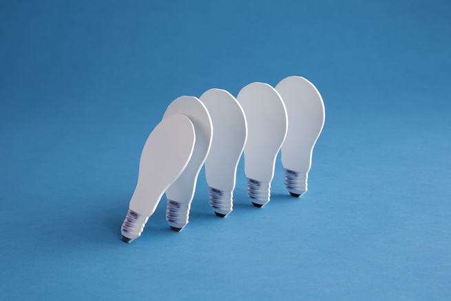 5 flat pictures of lightbulbs lined up like dominoes with the first one tipping over the next one on blue background