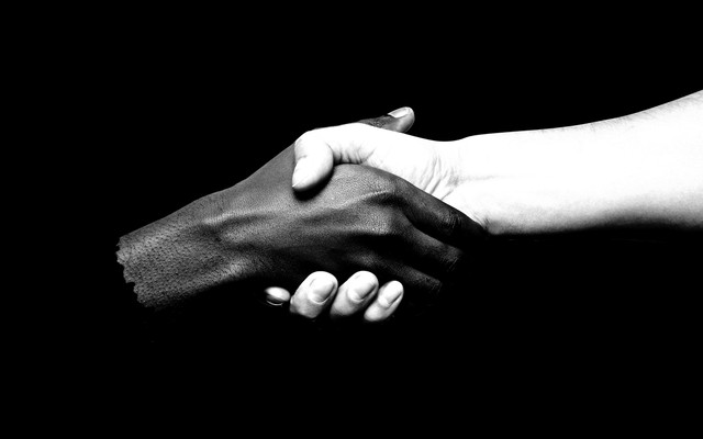 An illustration of two hands—one black, and one white—shaking.
