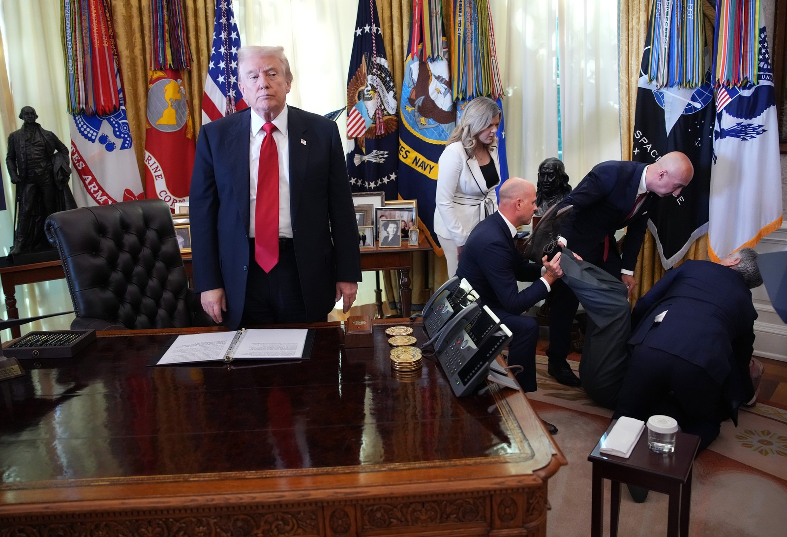 President Donald Trump stands by as attendees help a guest after he collapsed during during an event in the Oval Office.
