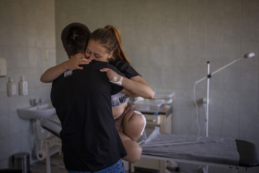 A man carries a woman recovering from injuries inside a hospital room.