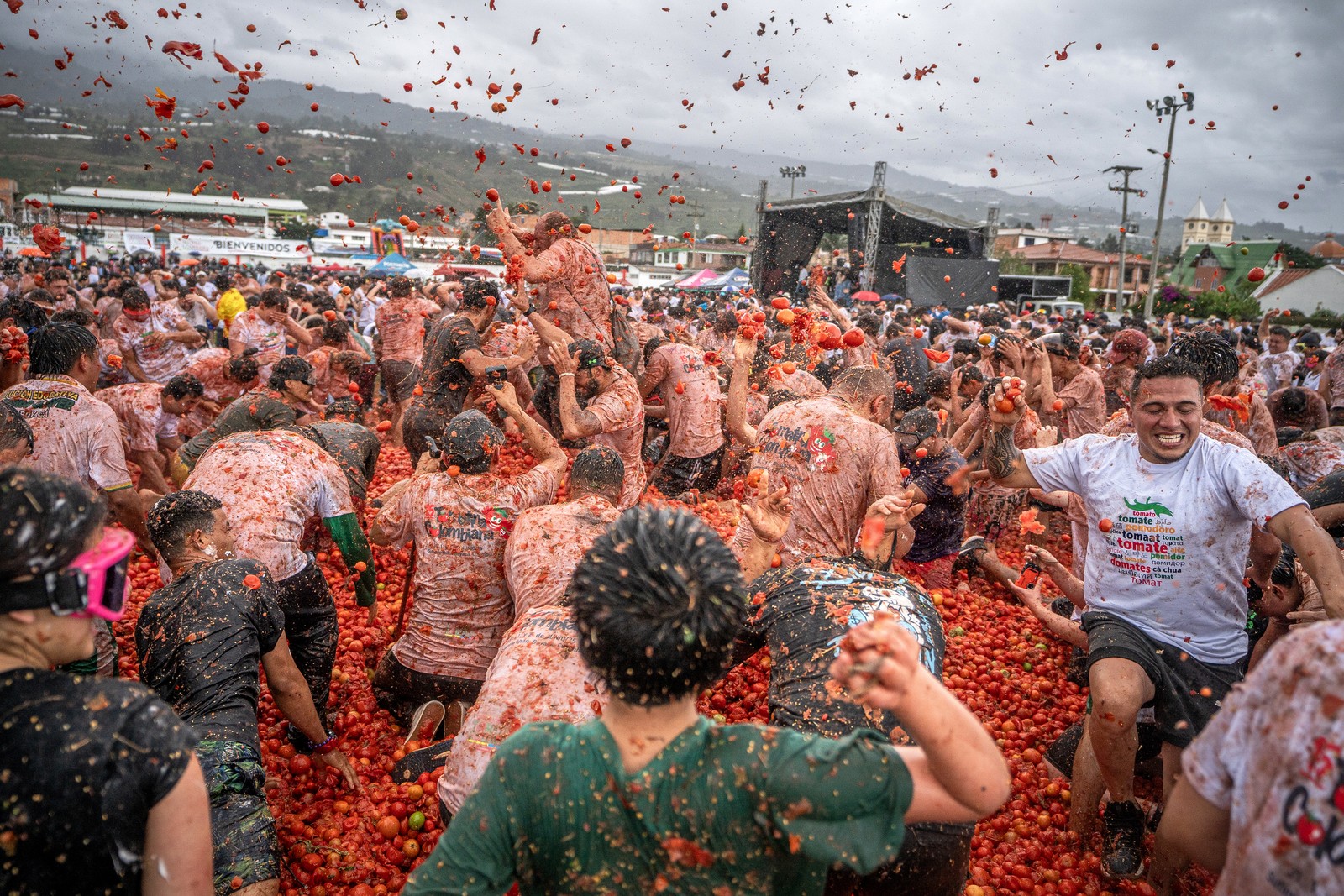 A large crowd of festival-goers throw hundreds of tomatoes at each other.