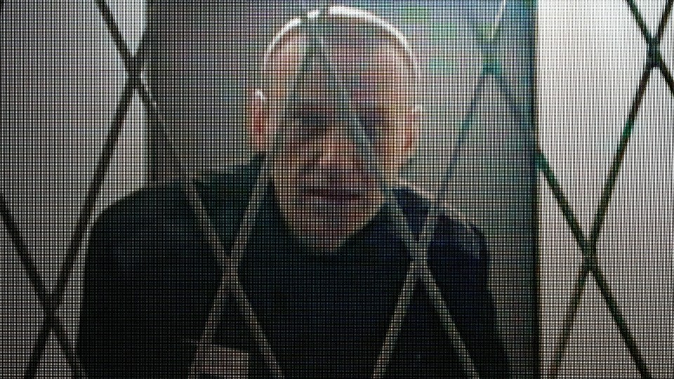 Navalny, behind a security fence, looking at the camera