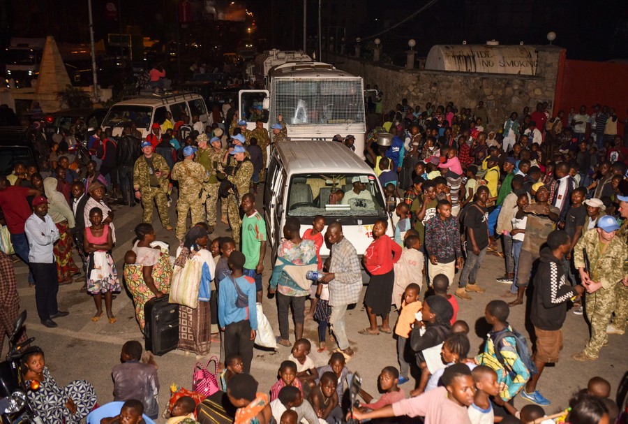 People gather in a street at night near United Nations soldiers.