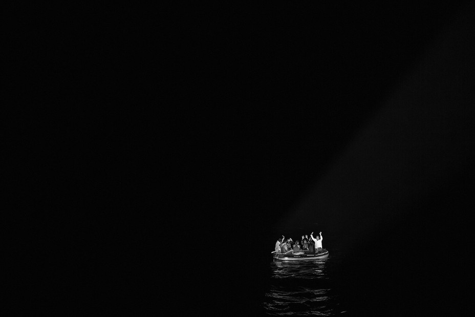 A boat full of migrants illuminated by the flashlights of the Turkish Coast Guard in Bodrum, Turkey