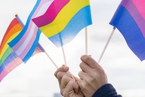 Image of hands holding a pride flag, bisexual pride flag, transgender flag, and pansexual flag