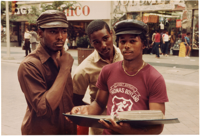 photo of 3 people on city street, one holding a large 3-ring album