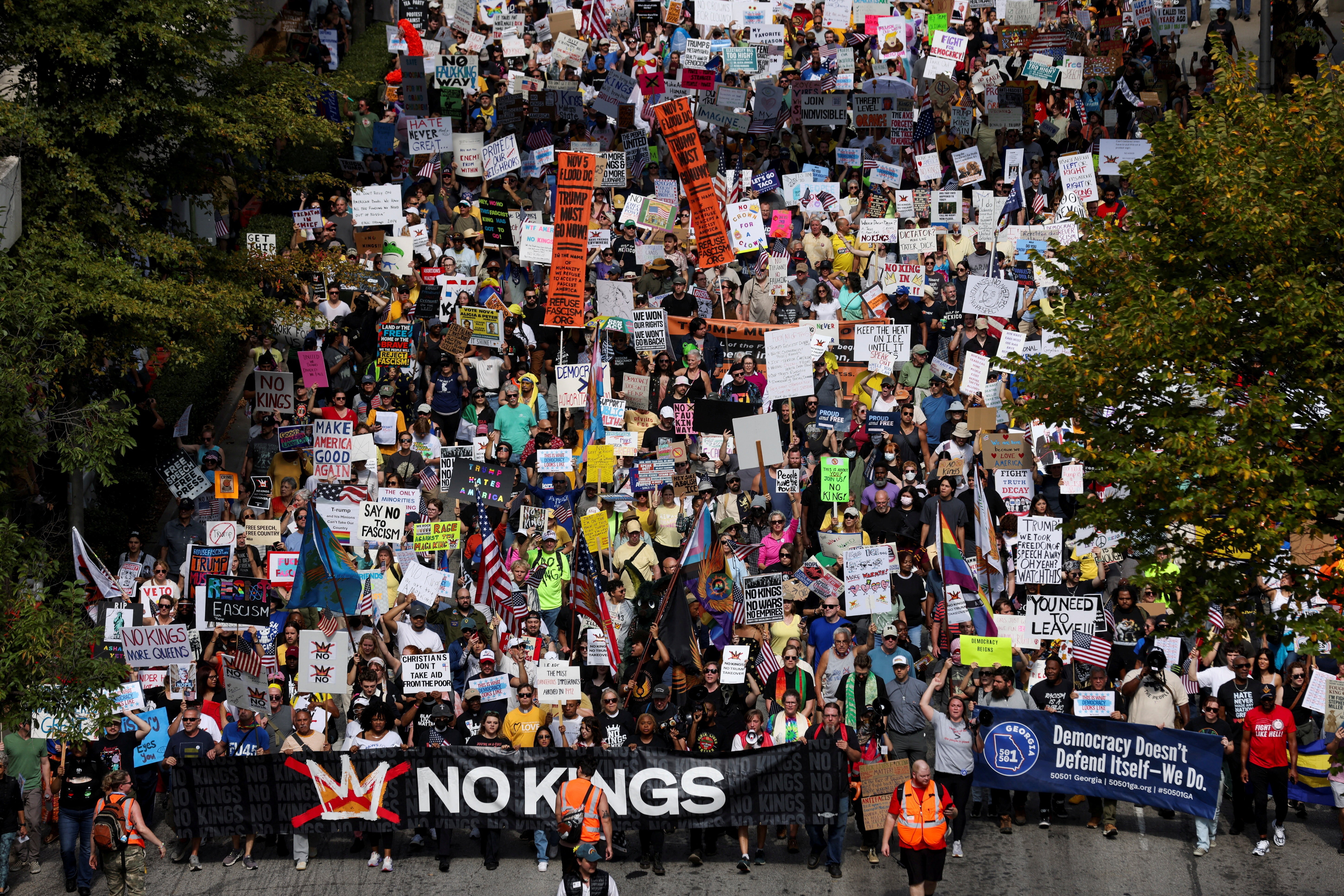 A crowd of protesters marches downa street, carrying signs.