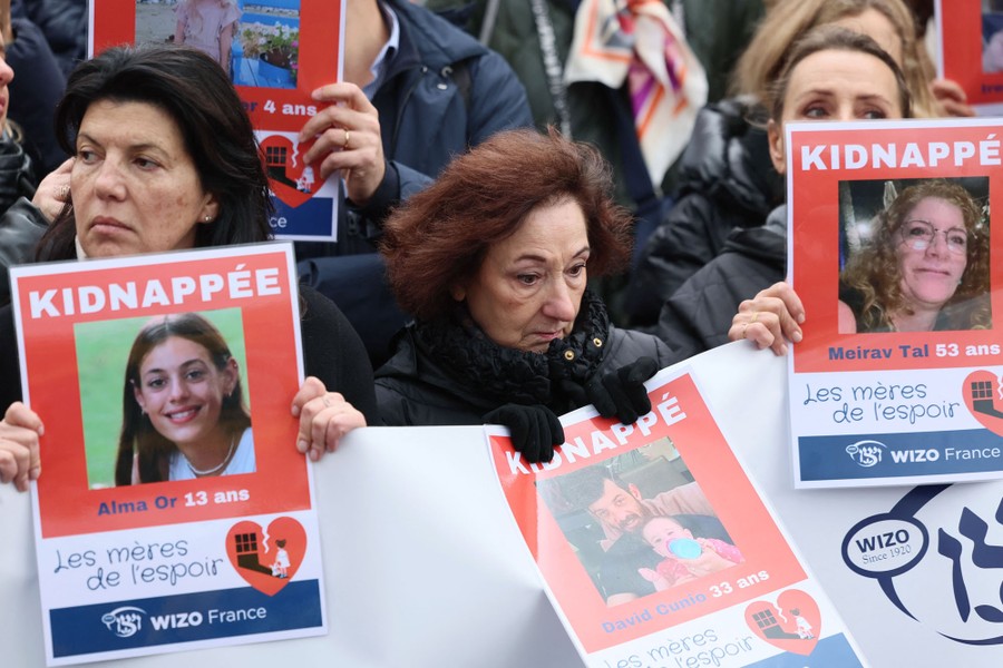 People gather for a demostration, holding signs with the names and faces of kidnapped people.