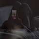 A teenager lying on a couch, looking at a cell phone.