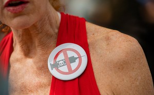 A woman wearing an anti-vax pin.