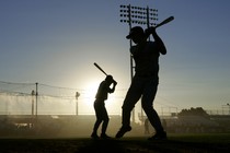 The silhouettes of swinging baseball players