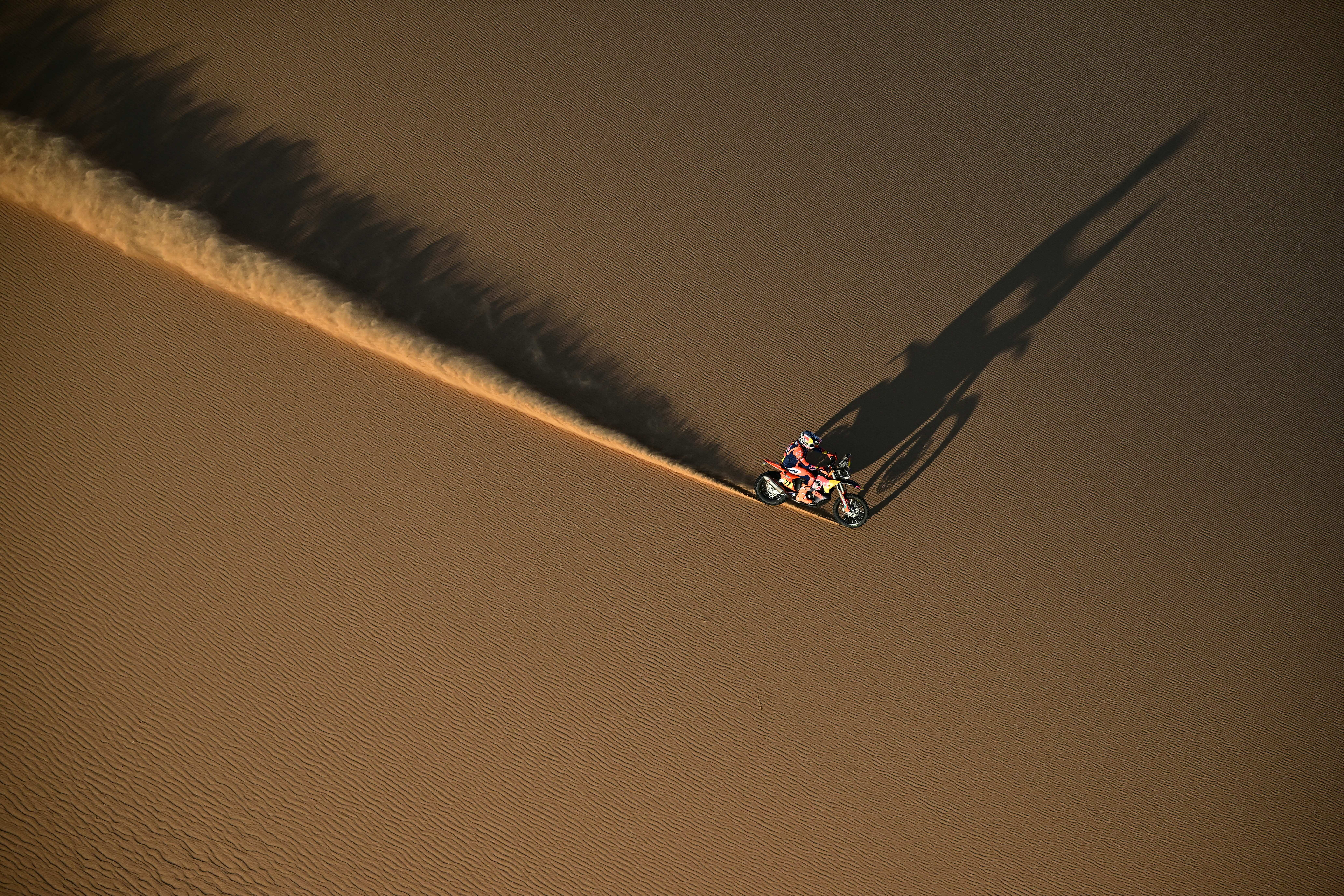 An aerial view of a motorcycle racer riding on a sand dune.