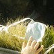 A hand, a face mask, and grass.