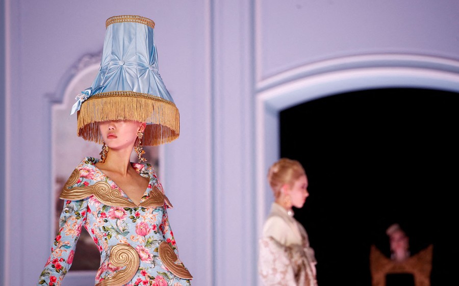 A model is seen wearing a hat that resembles an ornate lampshade.