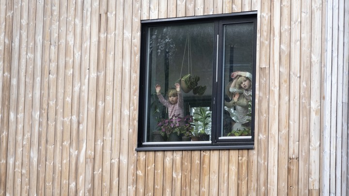 Three children stare out a window.