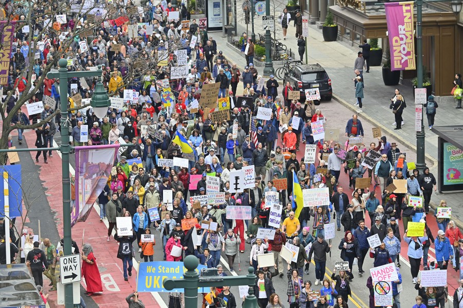 Sign-carrying protesters march down a city street.