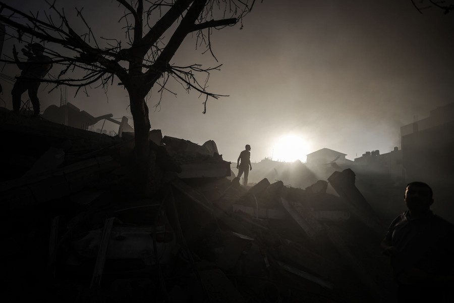 People walk among debris in a hazy smoke following an air strike.