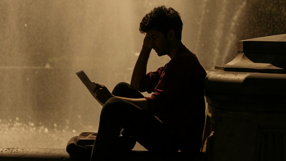 A boy reads a book in front of a fountain