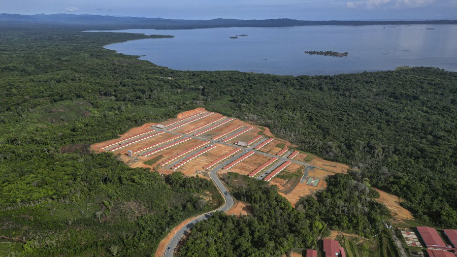 An aerial view of a newly built housing development set among forested hills and near a coastline
