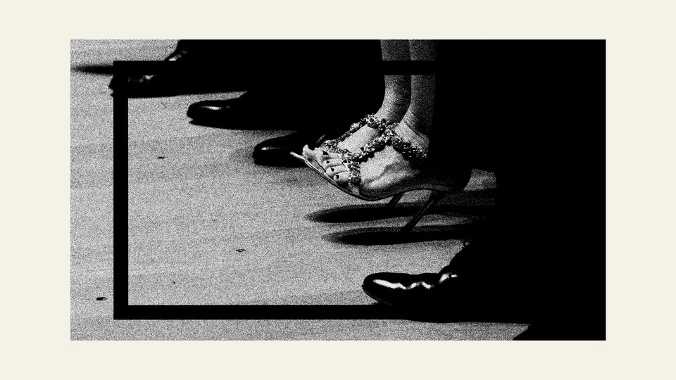 A photo showing men's shoes with one woman wearing heels sitting between them