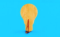 An illustration of a flat piece of wood that is shaped like a lightbulb and propped up by a wedge