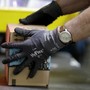 A person wearing a watch and gloves handles an Amazon package.