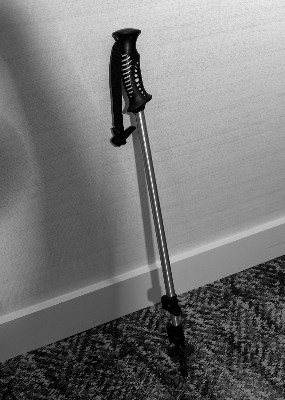 black-and-white photo of telescoping metal walking stick with handle leaning against wall