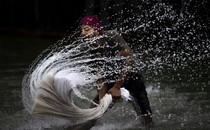 A person splashes water while washing clothes in a river.