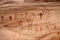 drawings of figures, shapes and handprints on a cliff wall