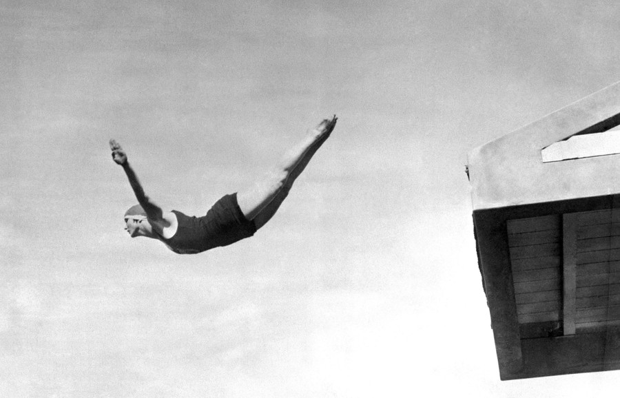 A diver stretches out in mid-air during a high dive.