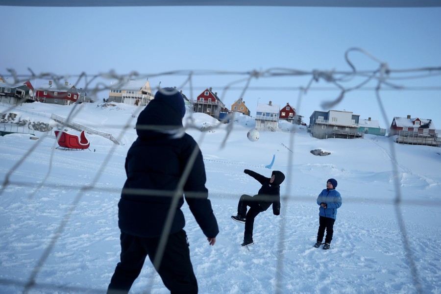 Children play soccer on a snow-covered field.
