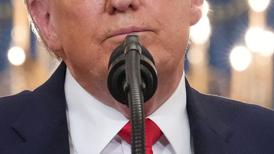 A close-up of Trump's face in front of a microphone, from the nose down