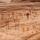 drawings of figures, shapes and handprints on a cliff wall