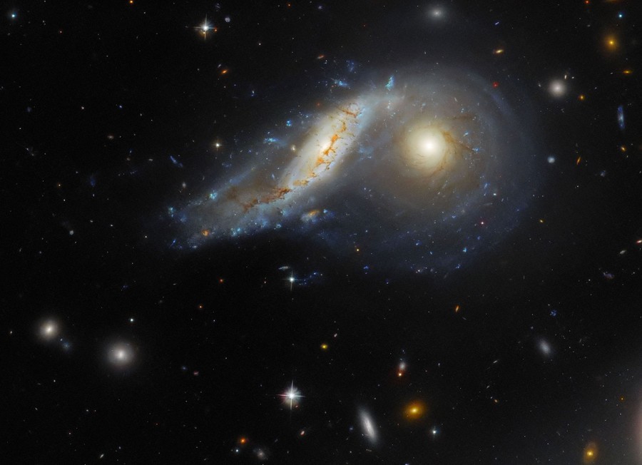 A telescopic view of two colliding spiral galaxies, with one tilted and slightly warped.