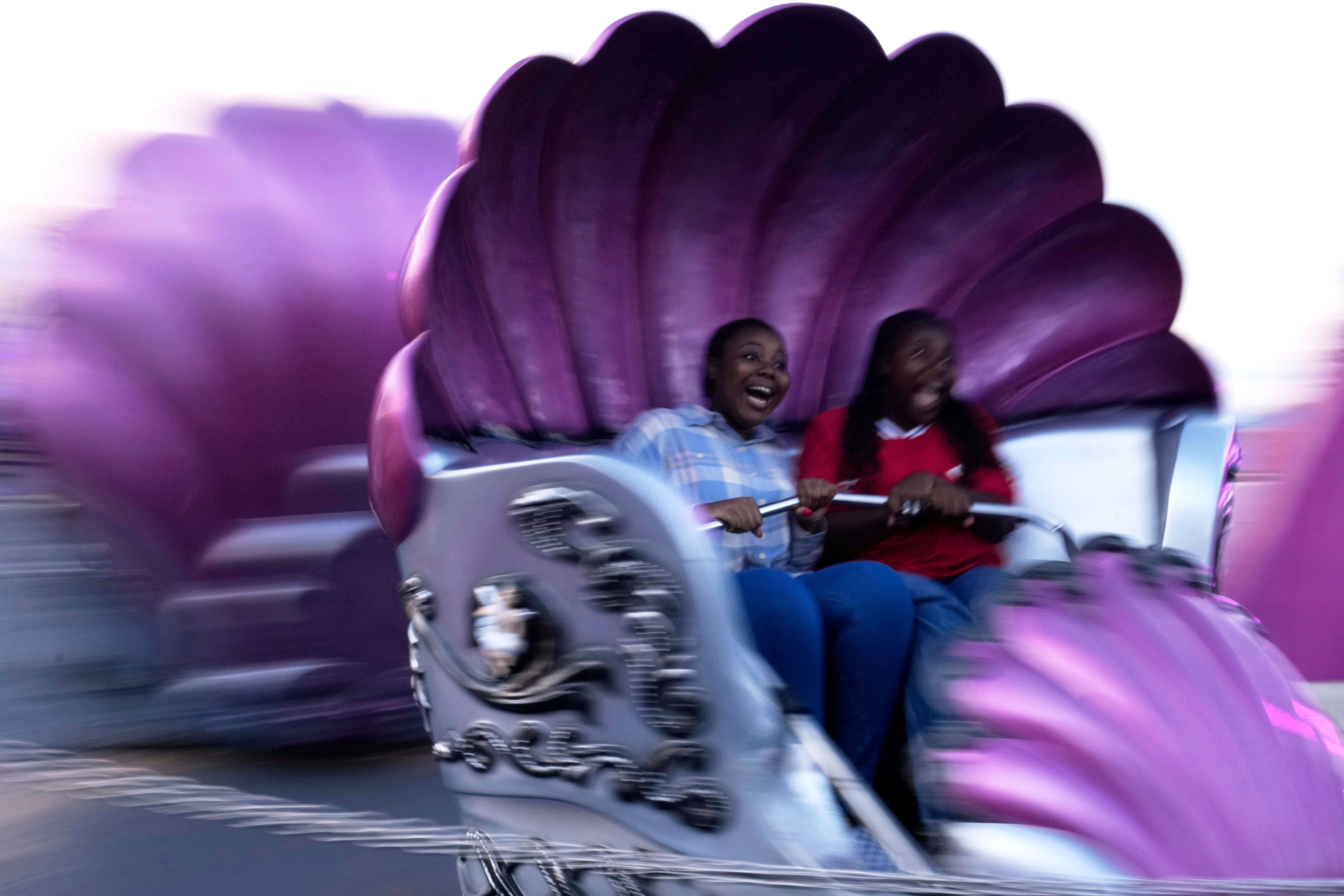 Two girls scream while enjoying a carnival ride, seen slightly blurred by their motion.